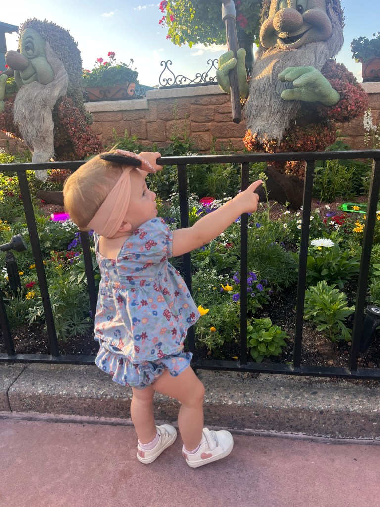 Baby girl looking at seven dwarves topiaries at at EPCOT Flower & Garden Festival. 